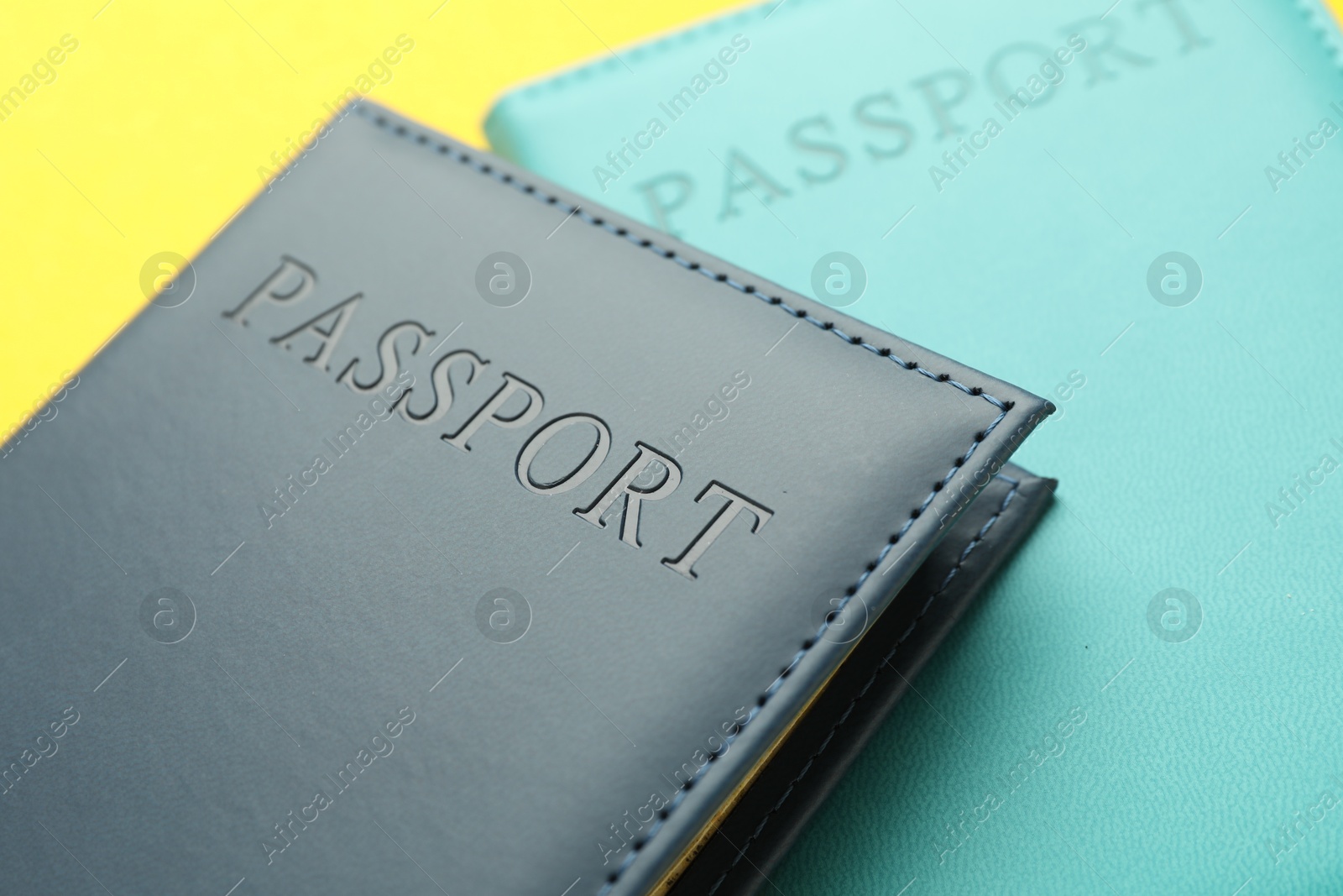 Photo of Passports in color covers on yellow background, closeup