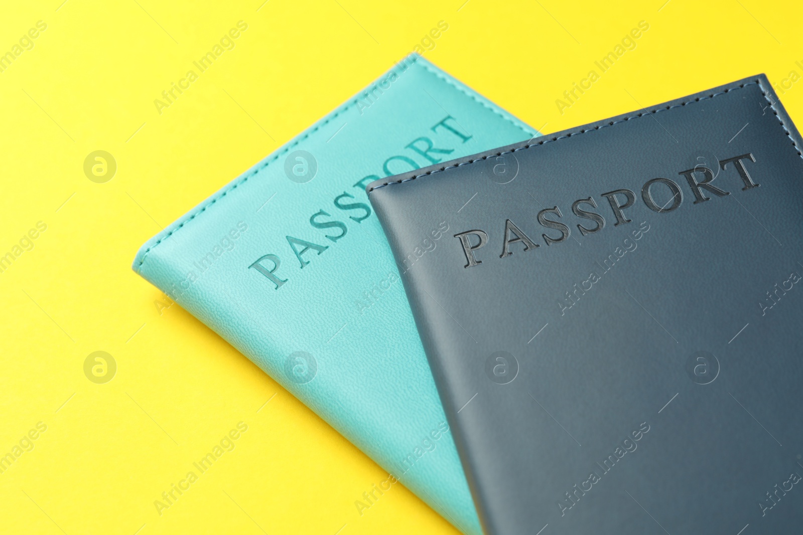 Photo of Passports in color covers on yellow background, closeup