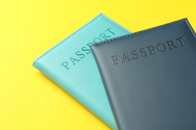 Photo of Passports in color covers on yellow background, closeup