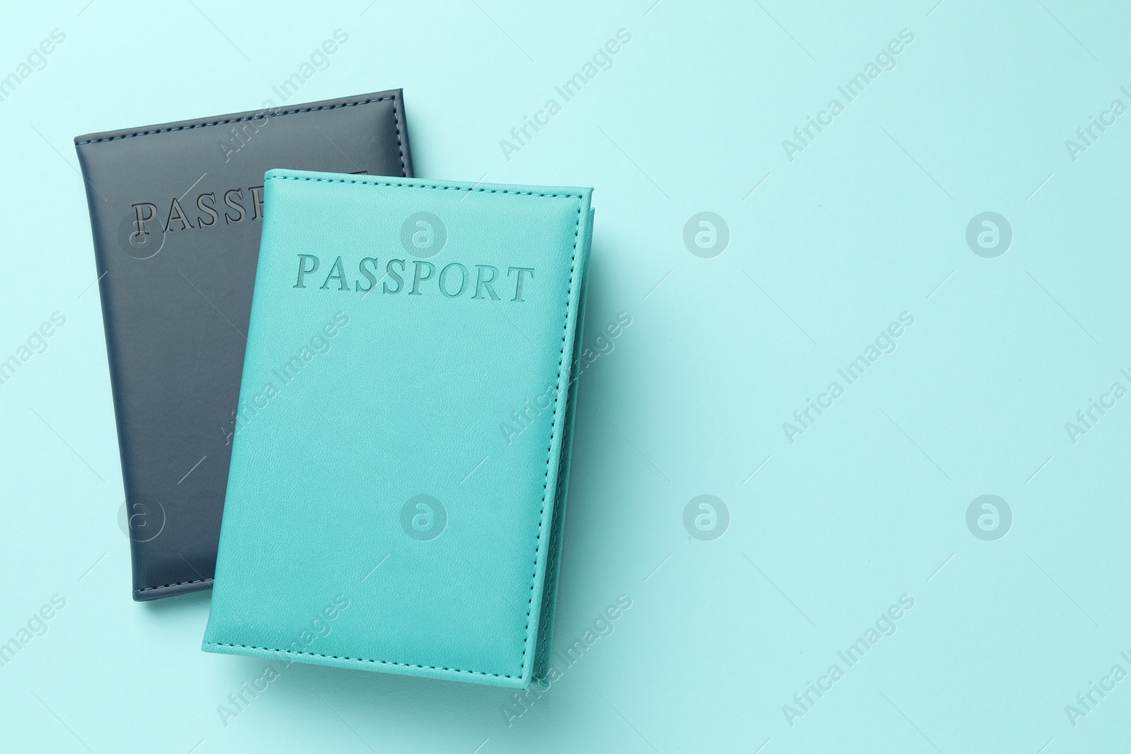 Photo of Passports in color covers on light blue background, top view. Space for text