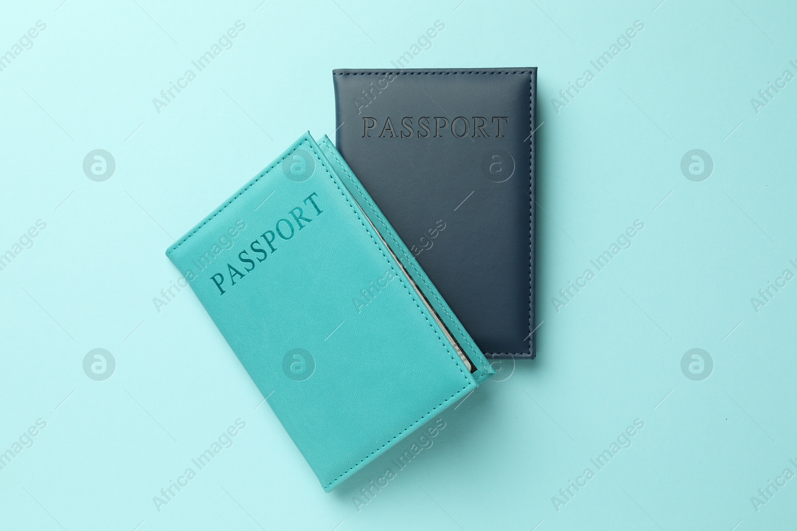 Photo of Passports in color covers on light blue background, top view