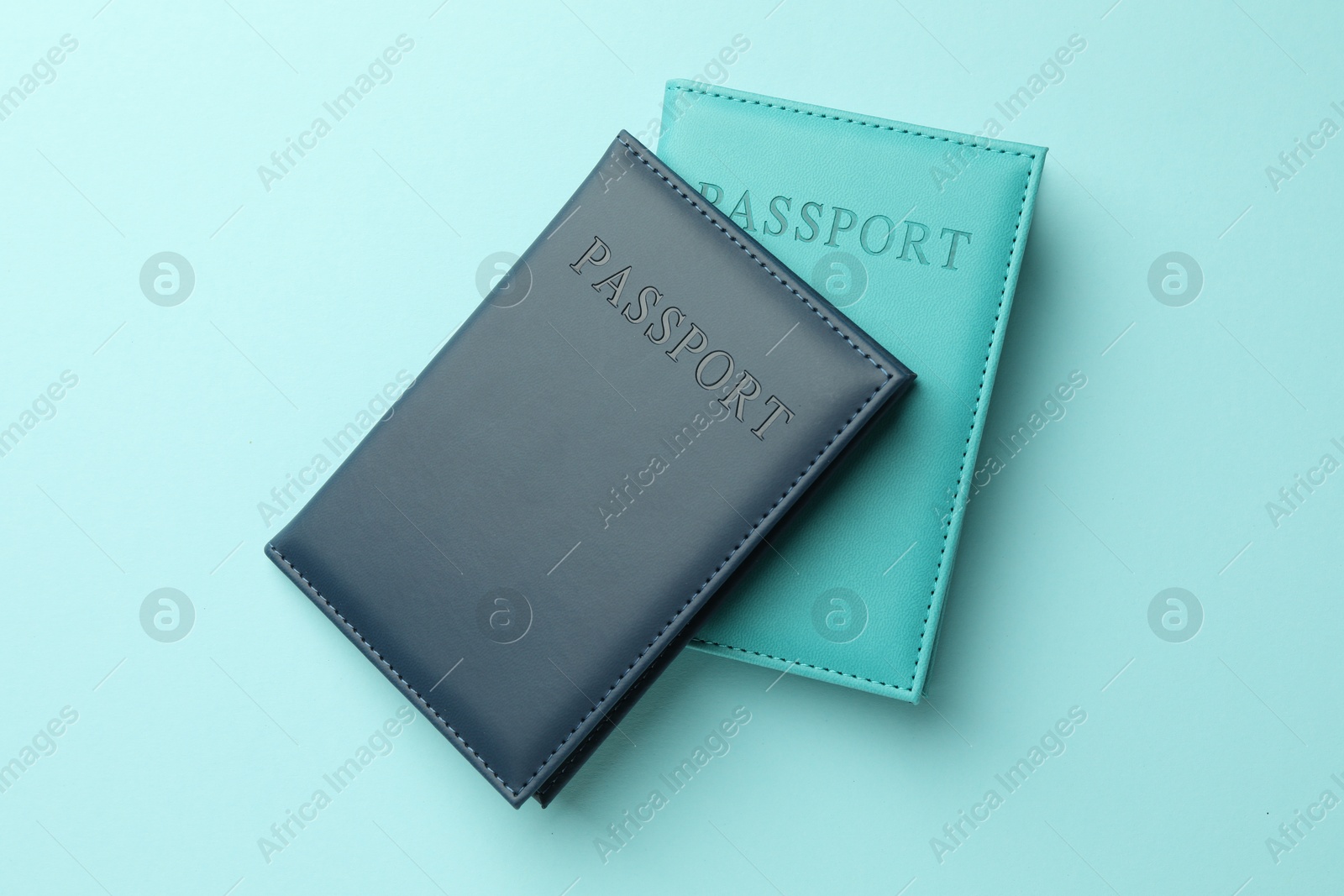 Photo of Passports in color covers on light blue background, top view