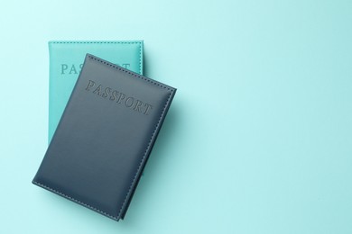 Photo of Passports in color covers on light blue background, top view. Space for text