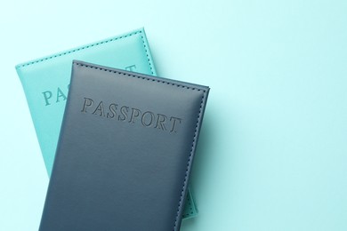 Photo of Passports in color covers on light blue background, top view. Space for text