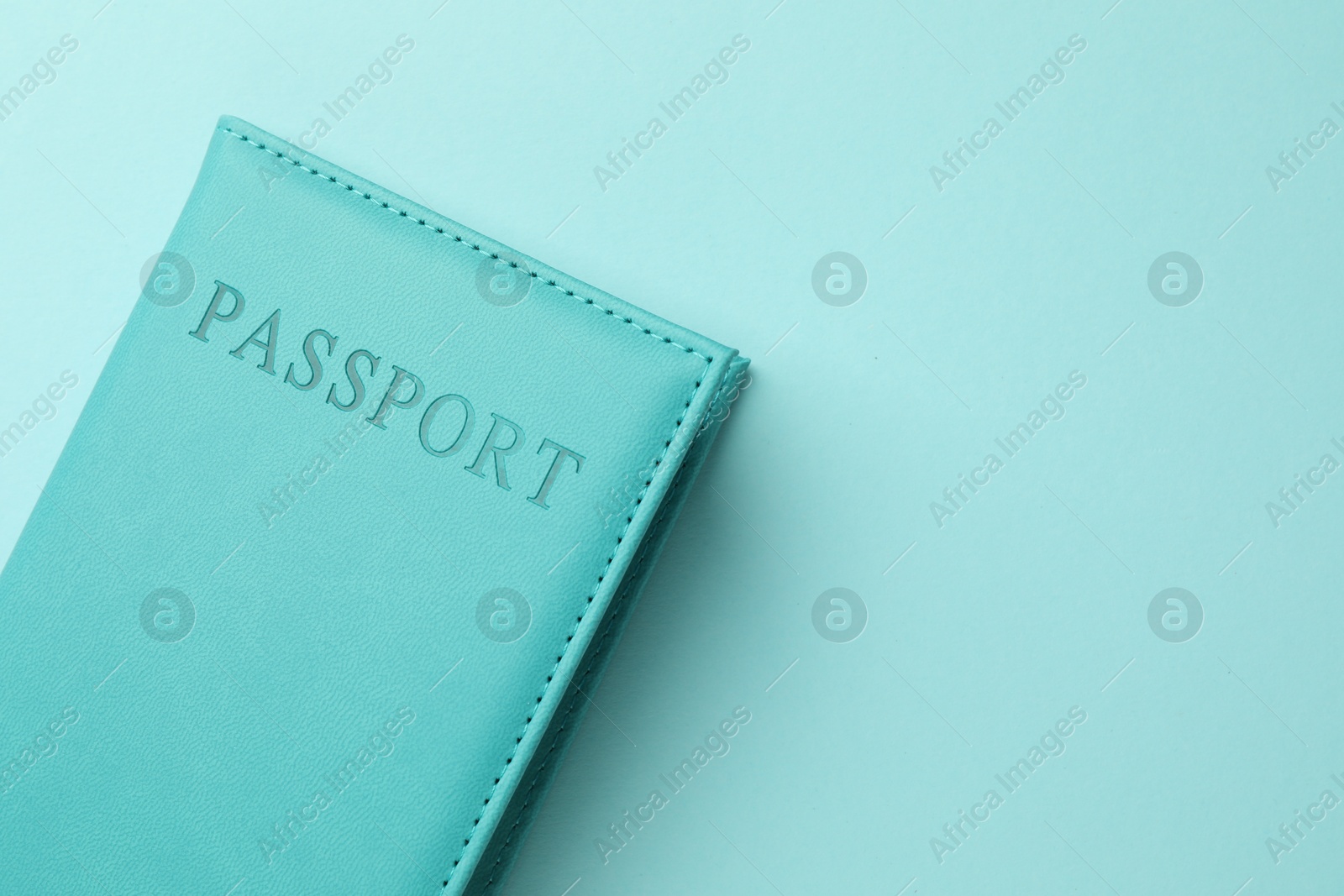 Photo of Passport in bright cover on light blue background, top view. Space for text