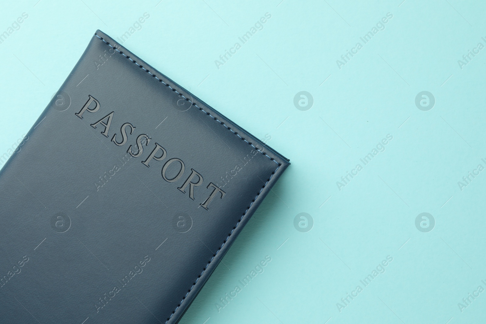 Photo of Passport in bright cover on light blue background, top view. Space for text