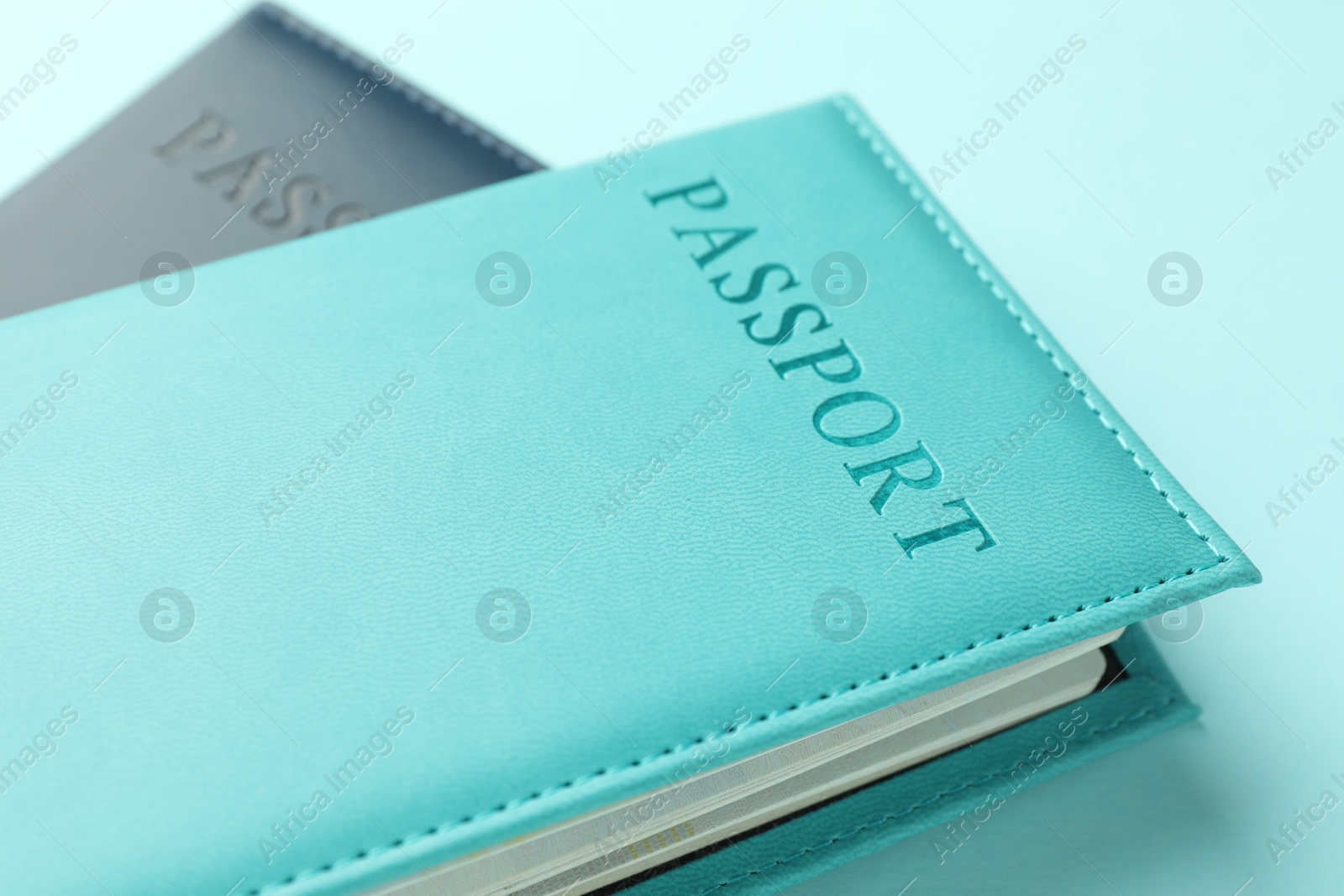 Photo of Passports in color covers on light blue background, closeup