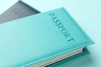 Photo of Passports in color covers on light blue background, closeup