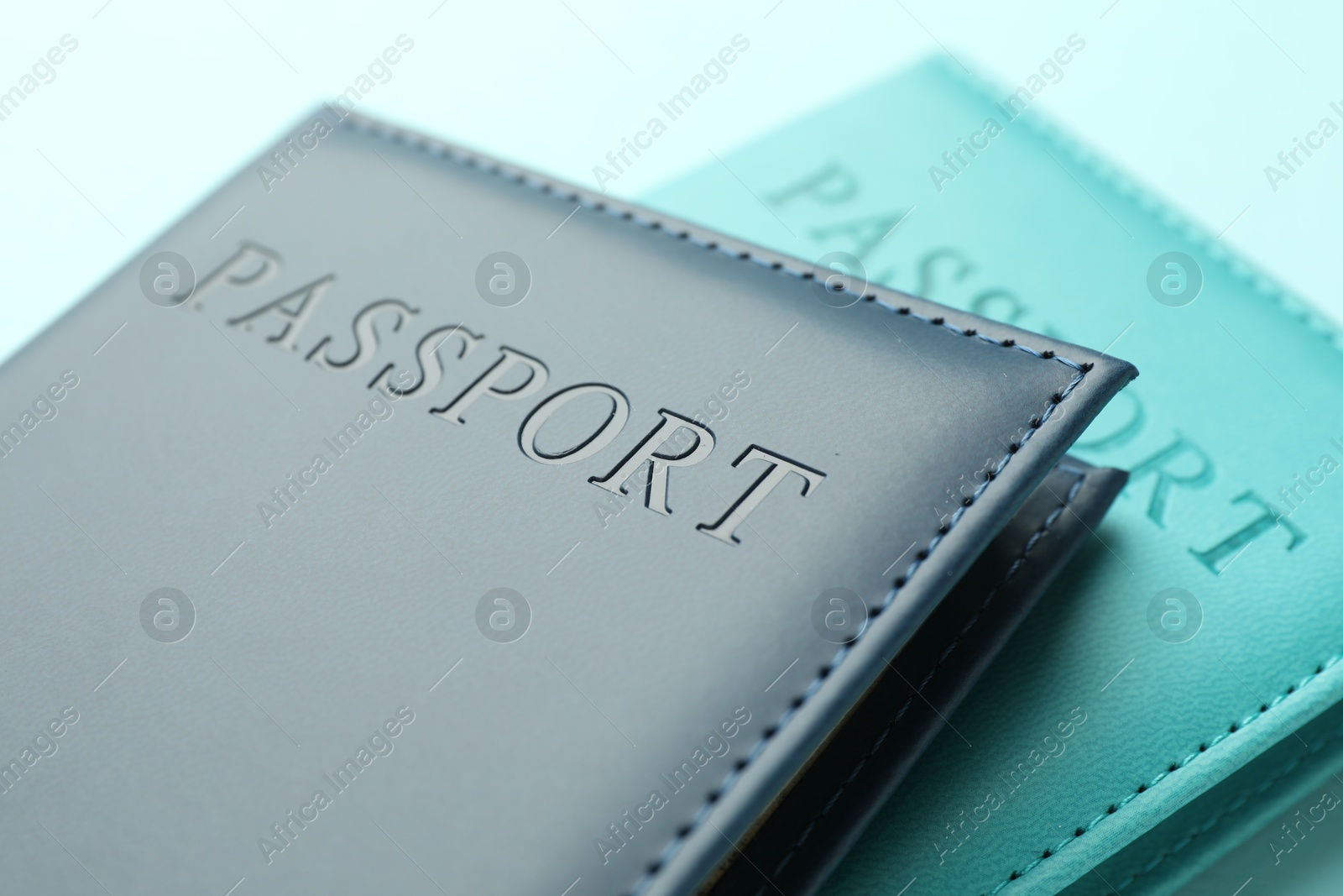 Photo of Passports in color covers on light blue background, closeup