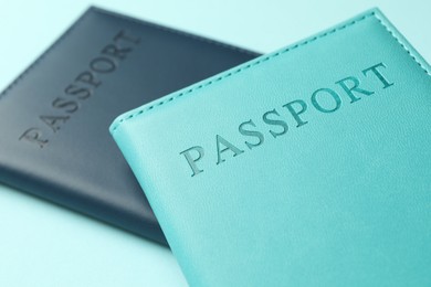 Photo of Passports in color covers on light blue background, closeup