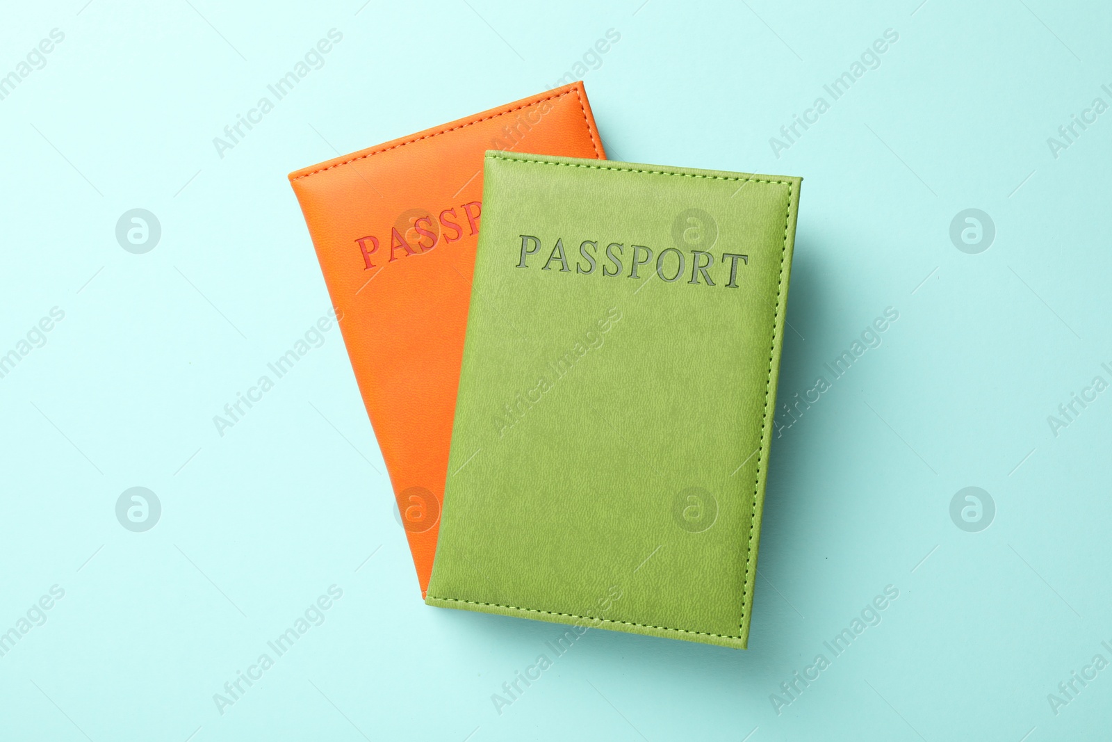 Photo of Passports in color covers on light blue background, top view