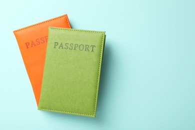 Photo of Passports in color covers on light blue background, top view. Space for text