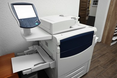 Photo of Modern printer with paper indoors. Printing house