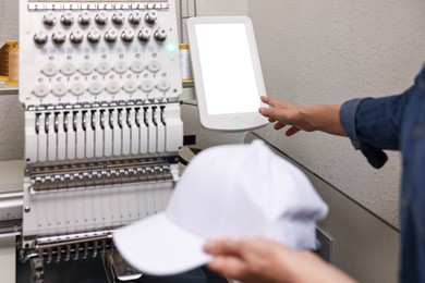 Photo of Woman with blank baseball cap for print using embroidery machine indoors, closeup