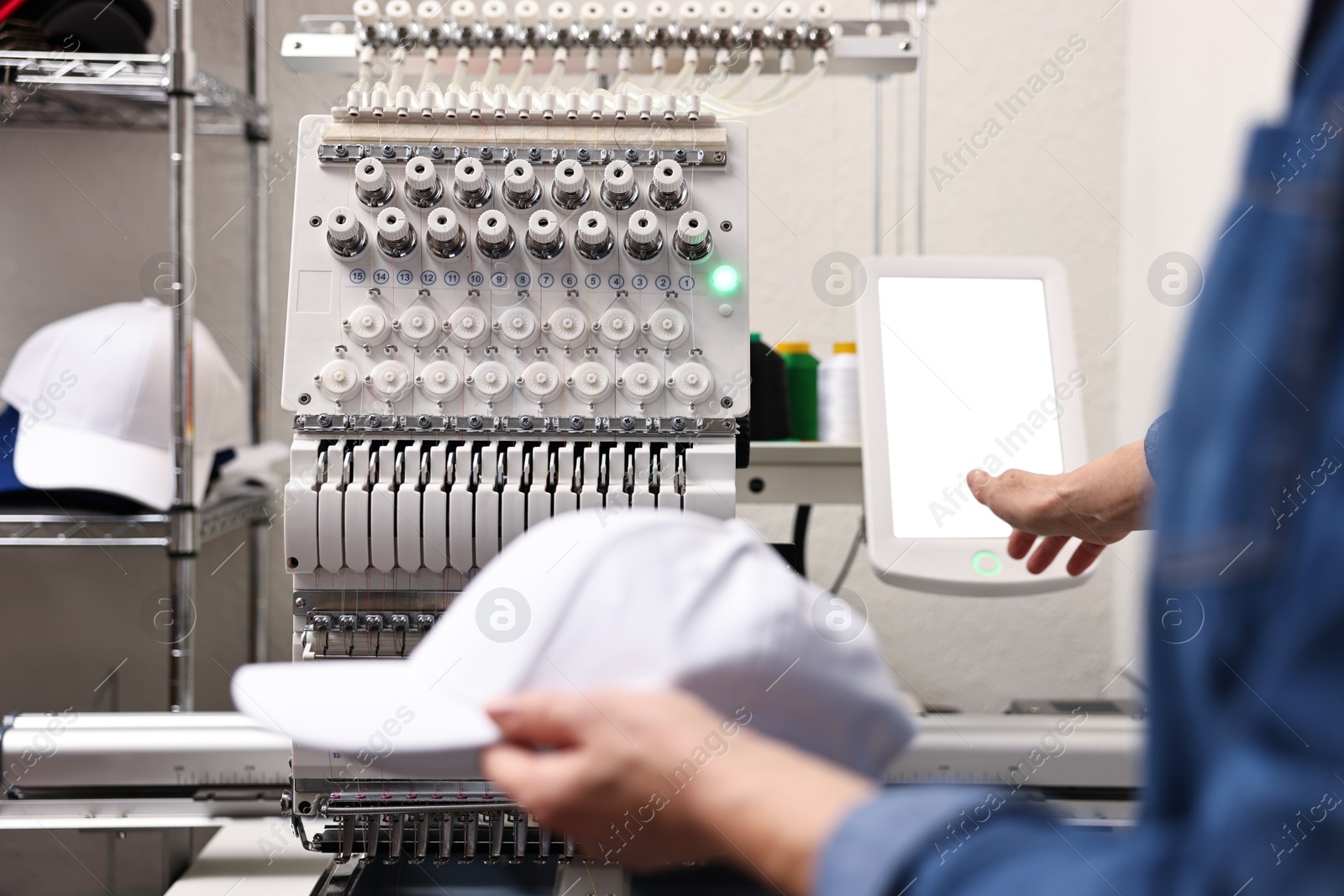 Photo of Woman with blank baseball cap for print using embroidery machine indoors, closeup