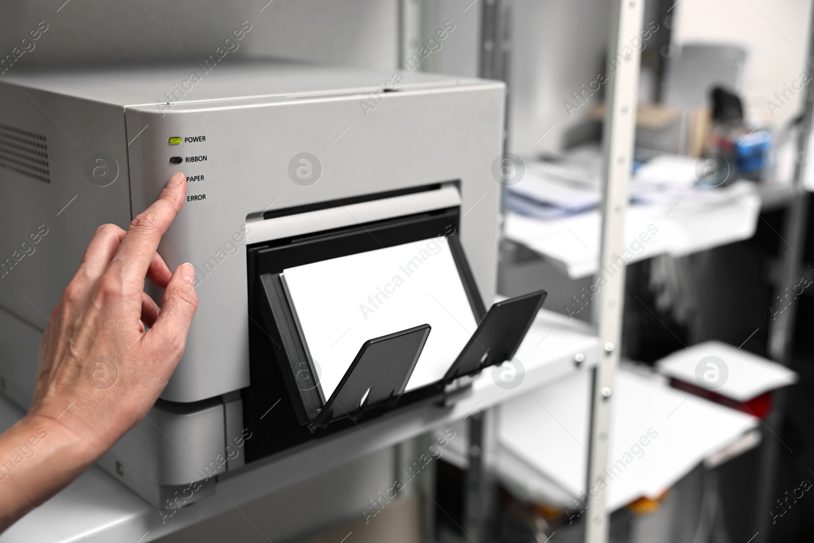 Photo of Woman using modern printer indoors, closeup. Printing house