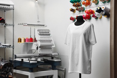 Photo of Mannequin with blank T-shirt for print and modern embroidery machine indoors