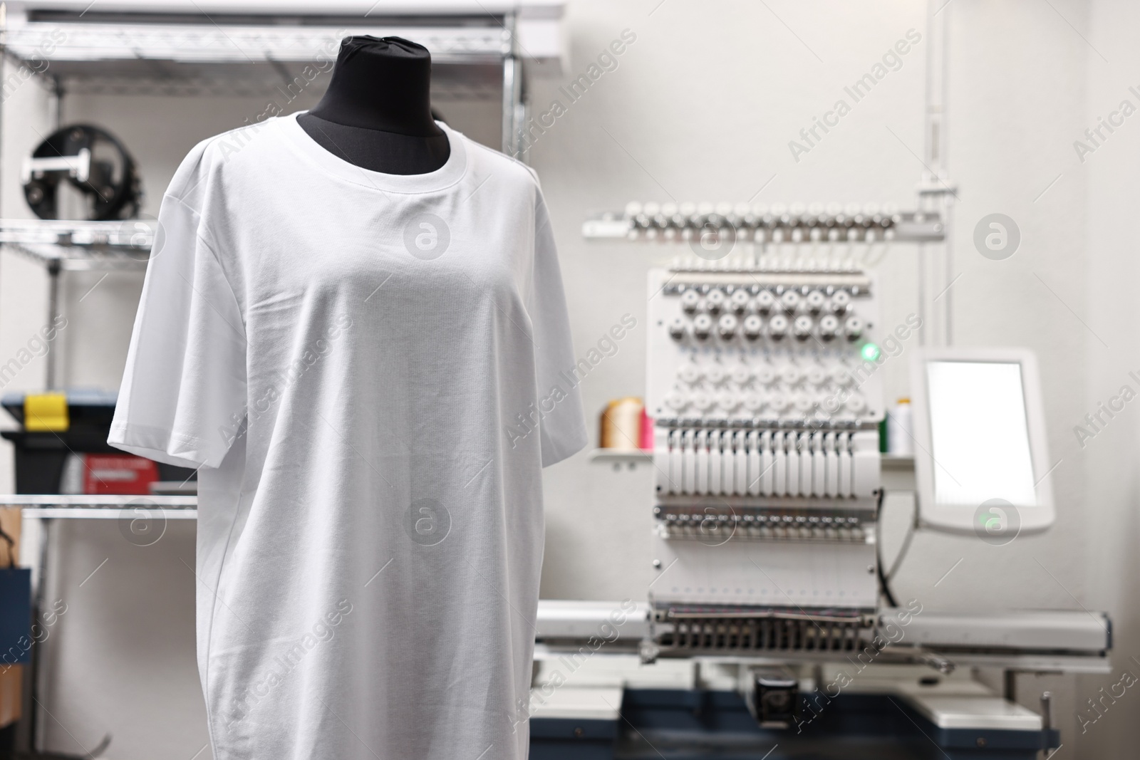 Photo of Mannequin with blank T-shirt for print and modern embroidery machine indoors