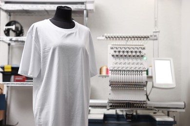 Photo of Mannequin with blank T-shirt for print and modern embroidery machine indoors