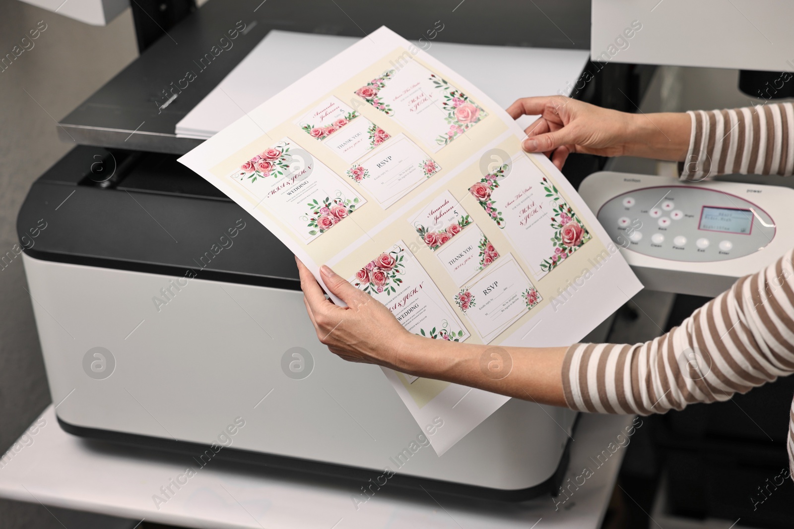 Photo of Woman with printed invitation cards near modern printer indoors, closeup. Printing house