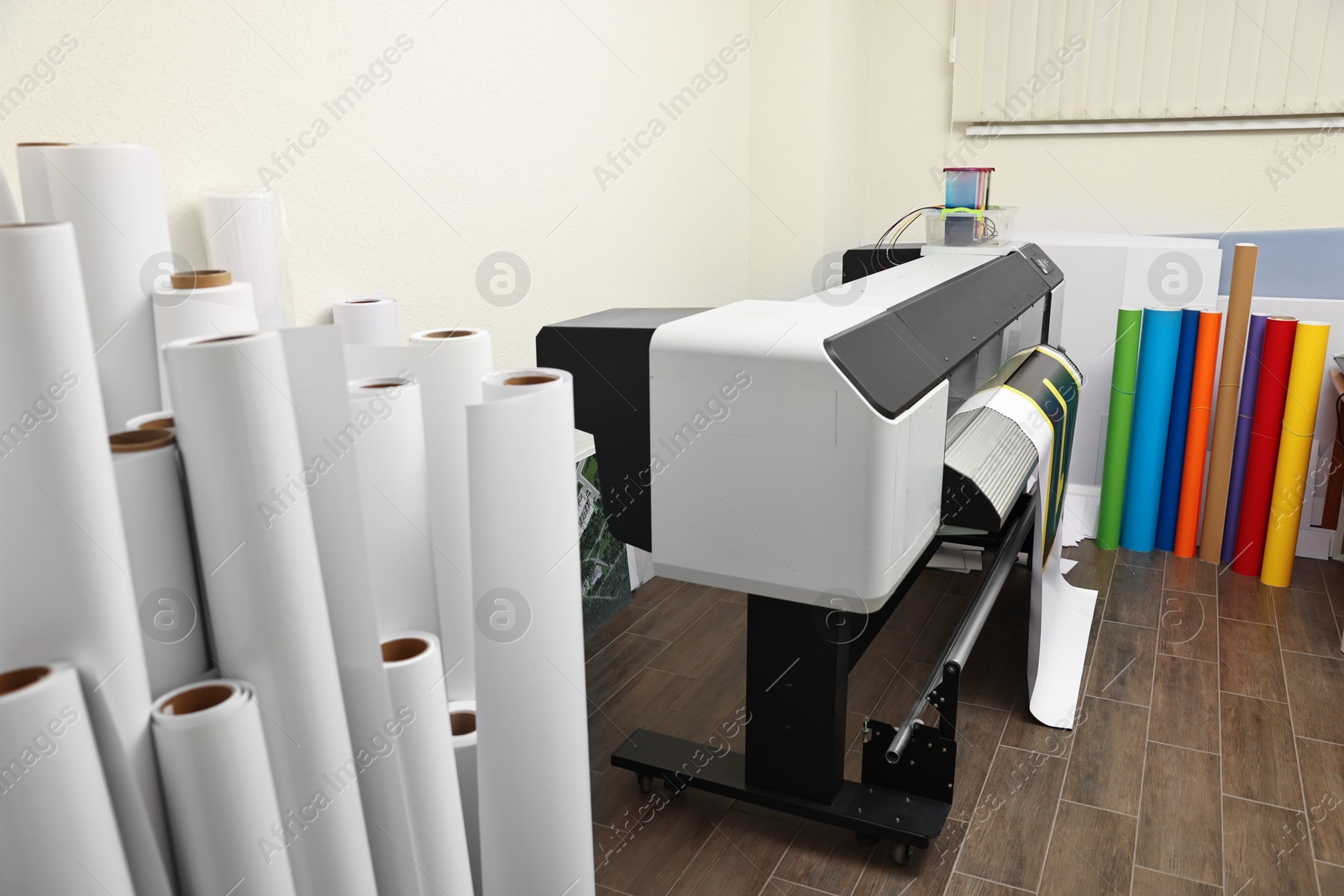 Photo of Wide-format printer and paper rolls indoors. Printing house