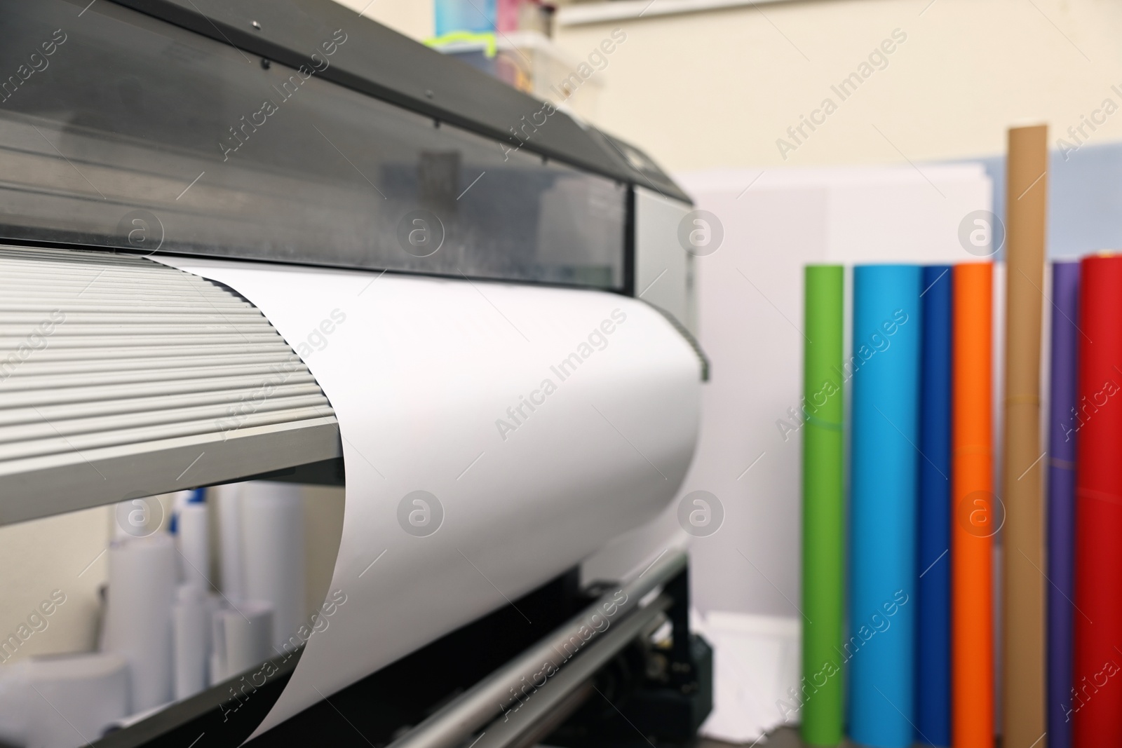 Photo of Wide-format printer with paper indoors, closeup. Printing house