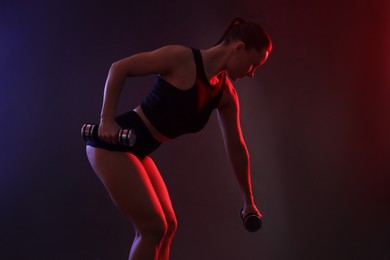 Photo of Woman exercising with dumbbells in smoke on dark background