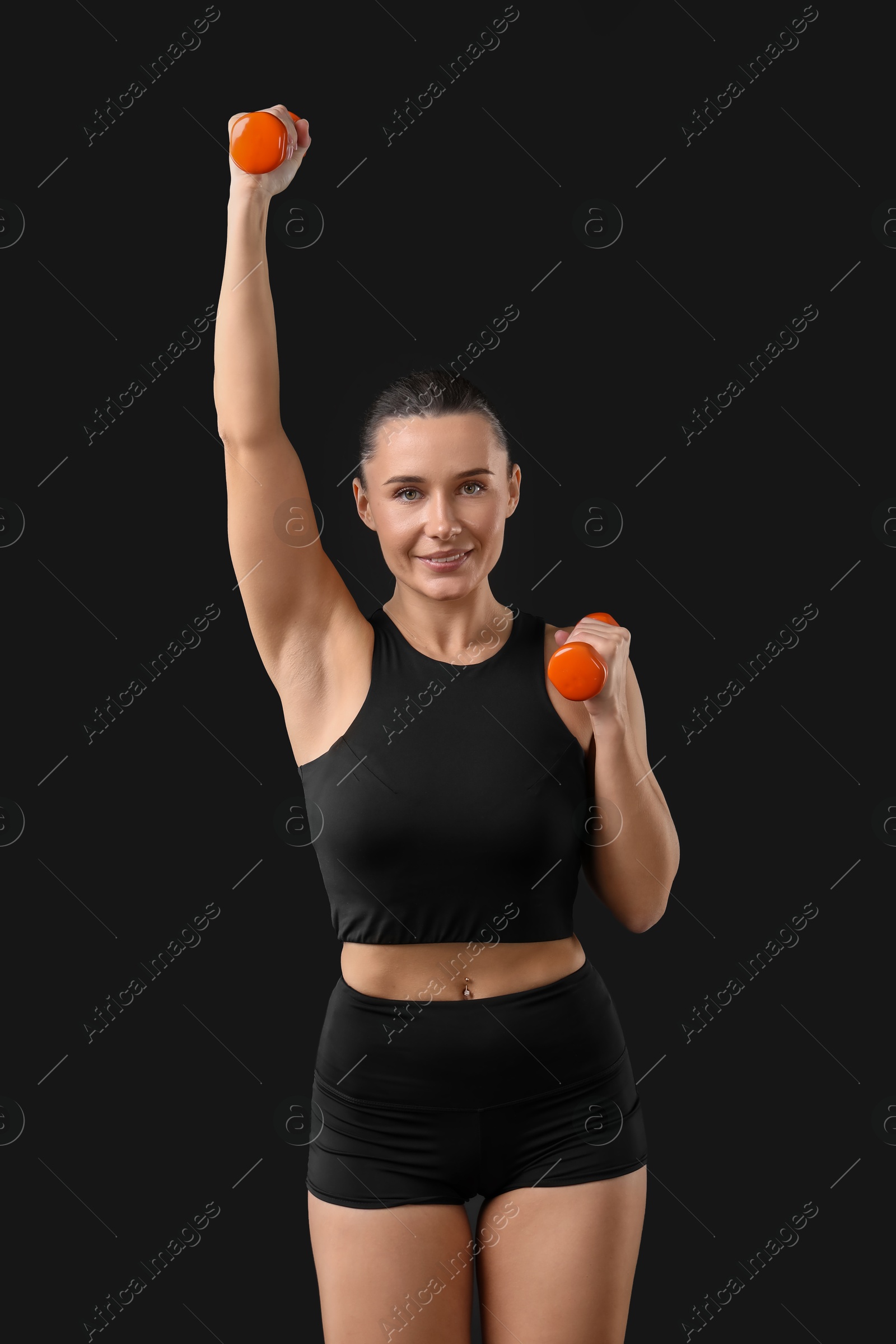 Photo of Woman exercising with dumbbells on black background