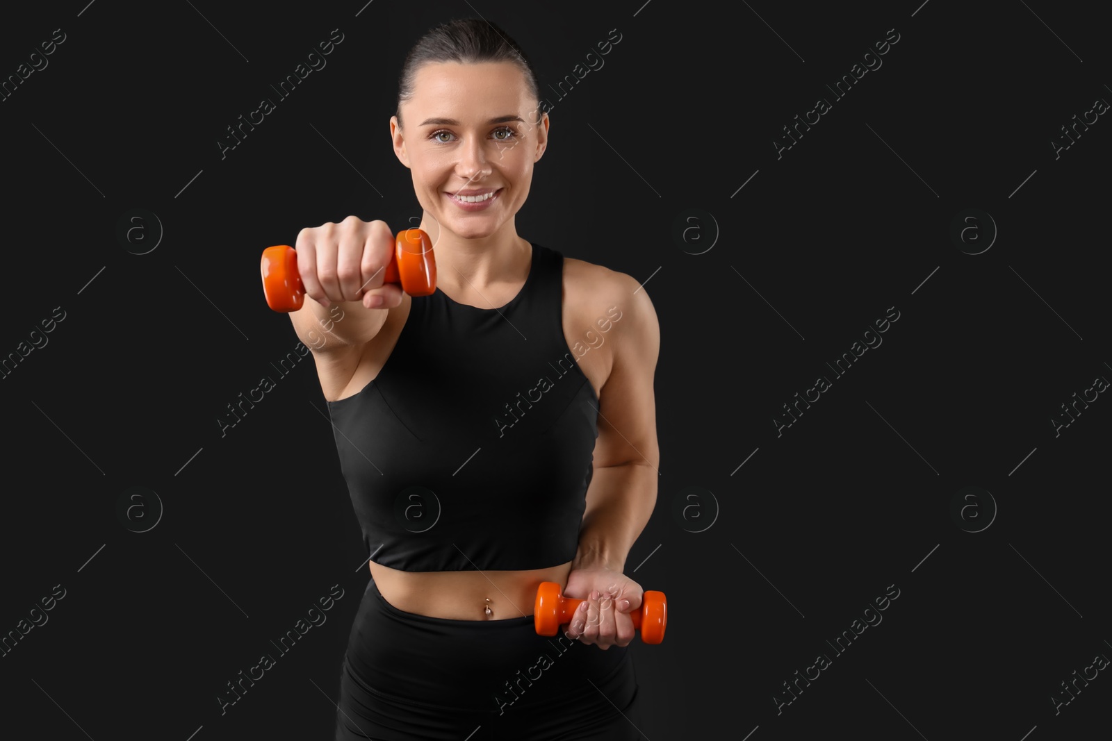 Photo of Woman exercising with dumbbells on black background, space for text