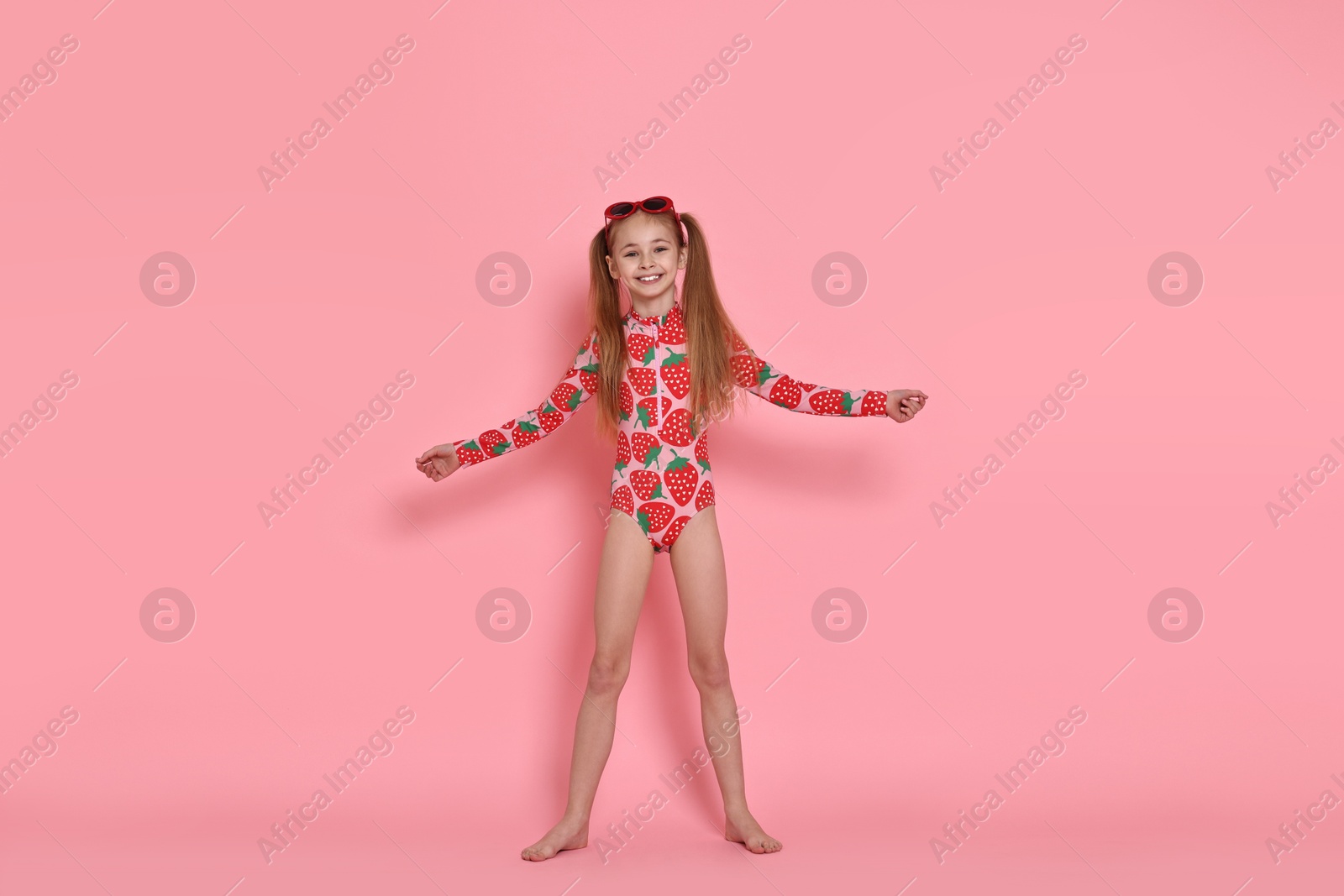 Photo of Happy girl in beachwear and sunglasses on pink background