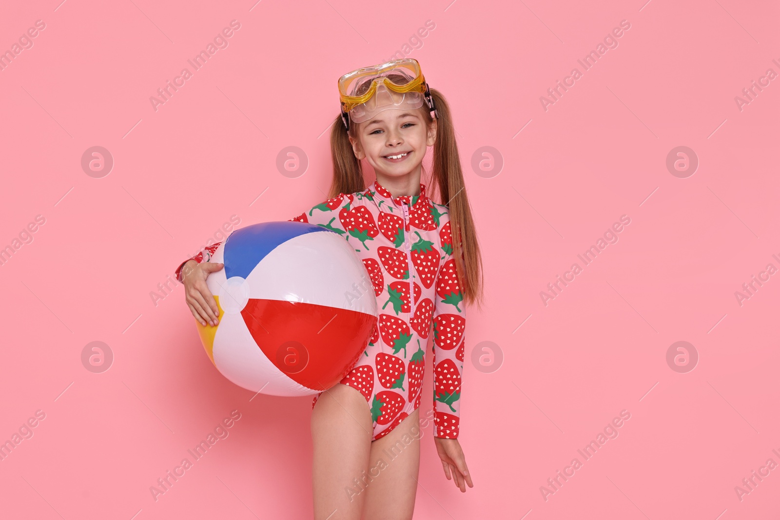 Photo of Happy girl in beachwear with diving mask and inflatable ball on pink background