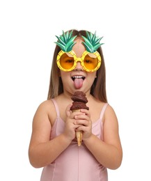 Photo of Cute little girl in swimsuit with funny sunglasses eating ice cream on white background