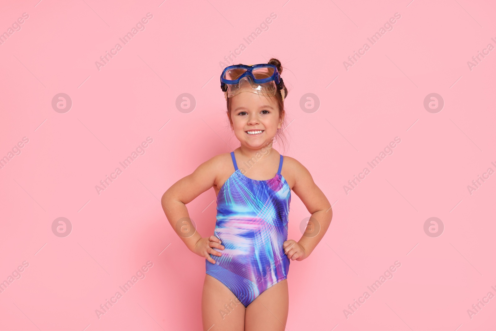 Photo of Cute little girl in swimsuit on light pink background