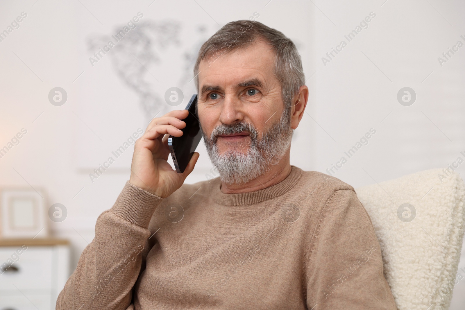 Photo of Mature man talking on smartphone at home