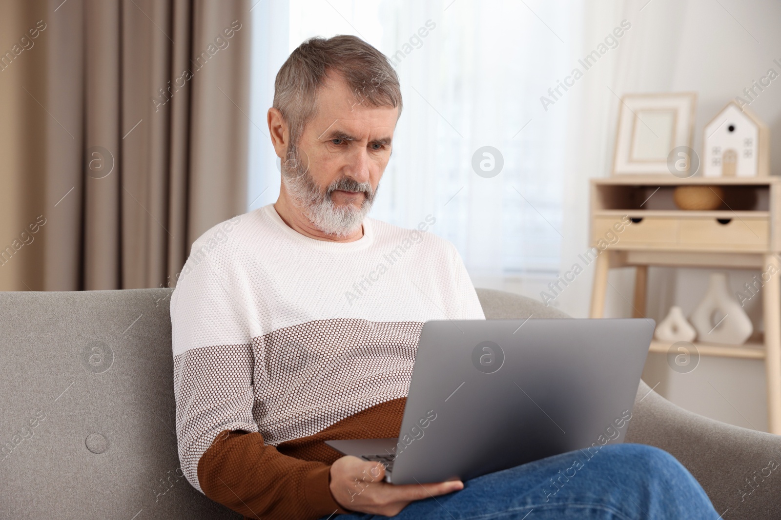 Photo of Mature man with laptop on sofa at home