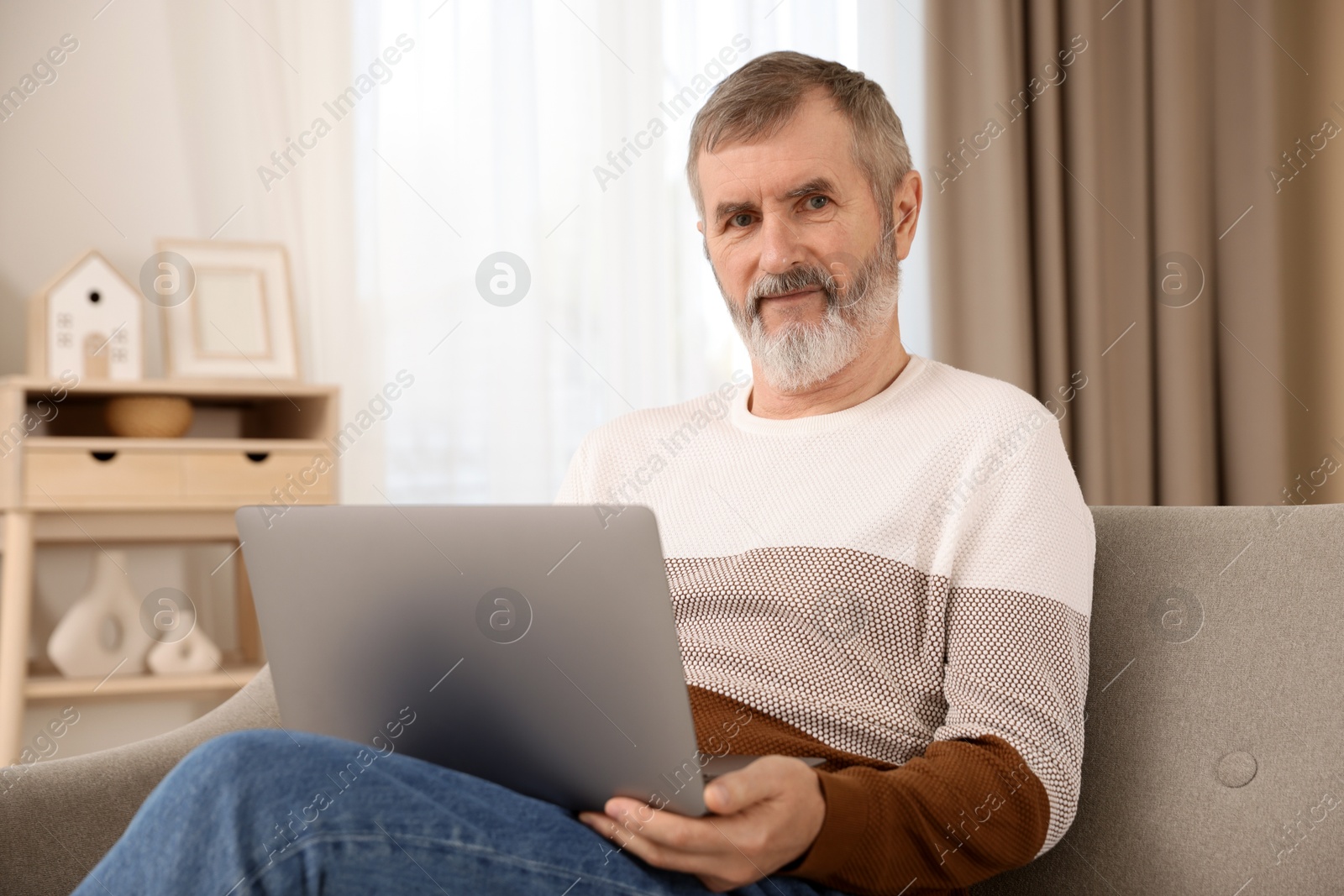 Photo of Mature man with laptop on sofa at home