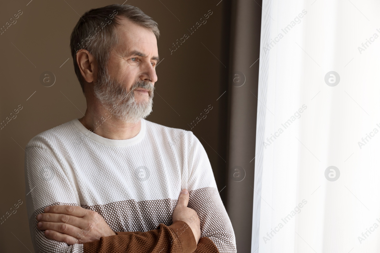 Photo of Mature man with crossed arms at home. Space for text