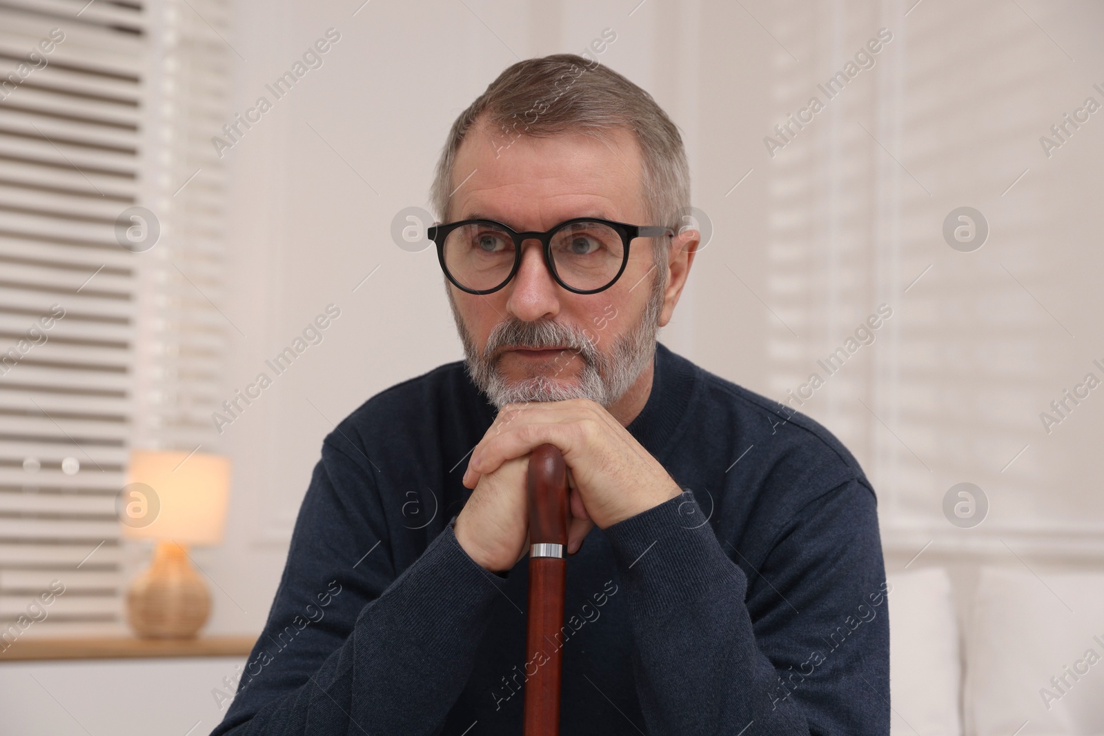 Photo of Mature man with walking cane at home