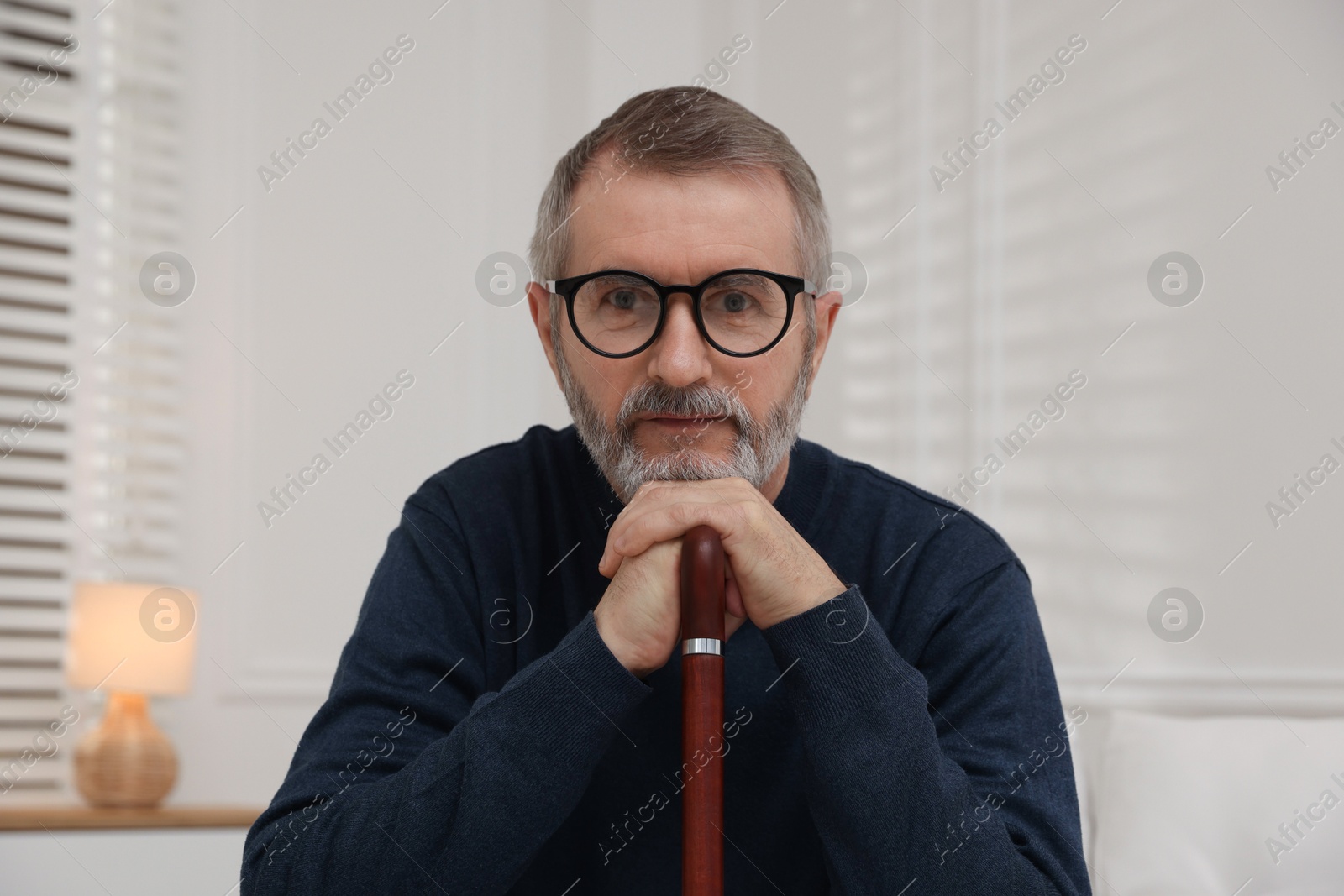 Photo of Mature man with walking cane at home