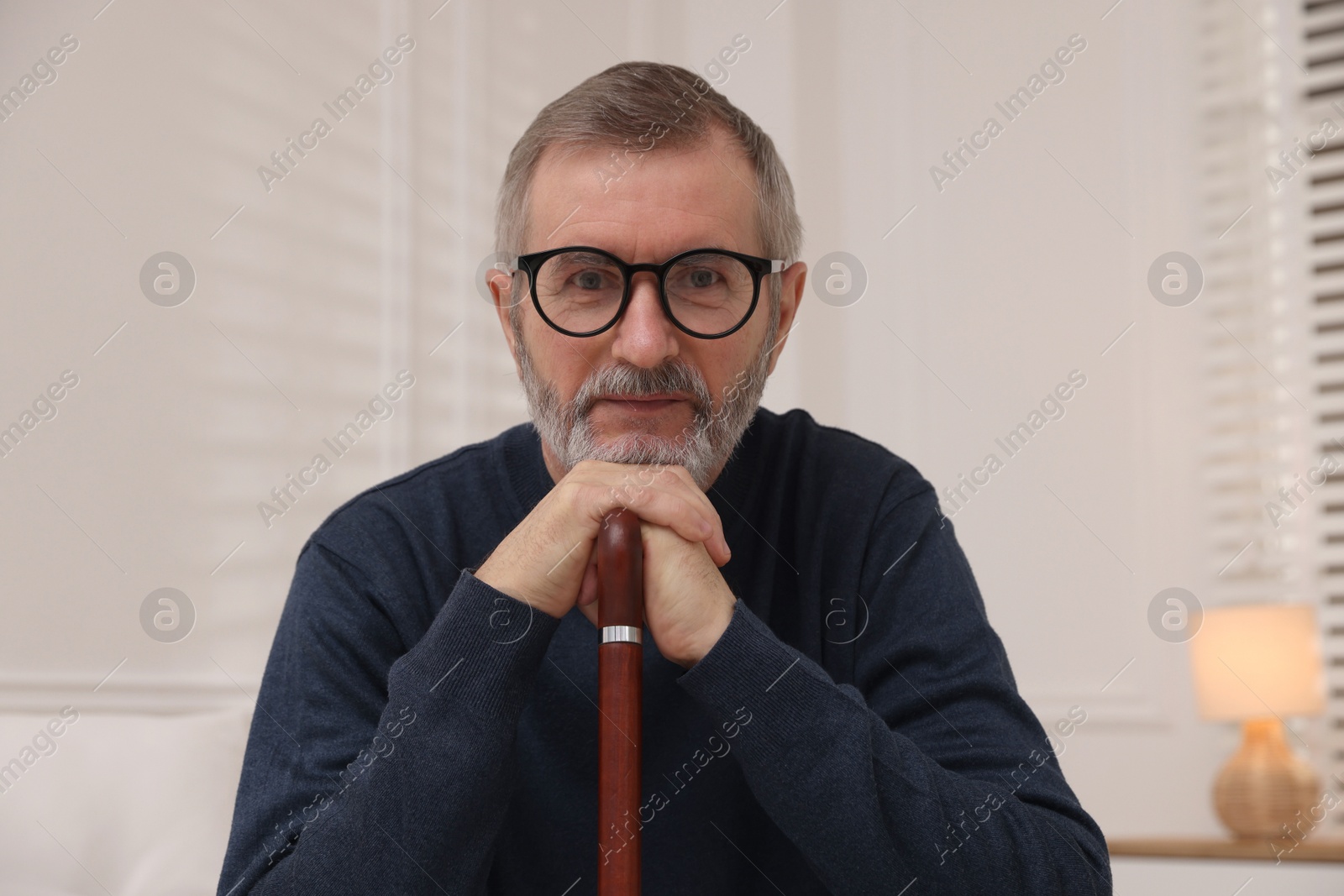 Photo of Mature man with walking cane at home