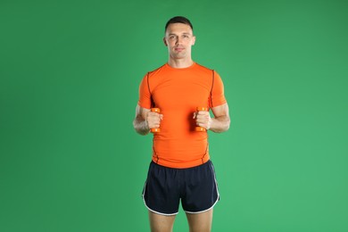 Man exercising with dumbbells on green background