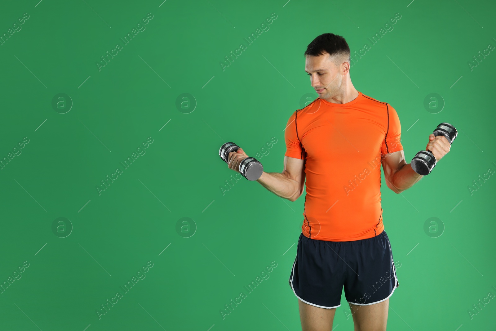 Photo of Man exercising with dumbbells on green background, space for text