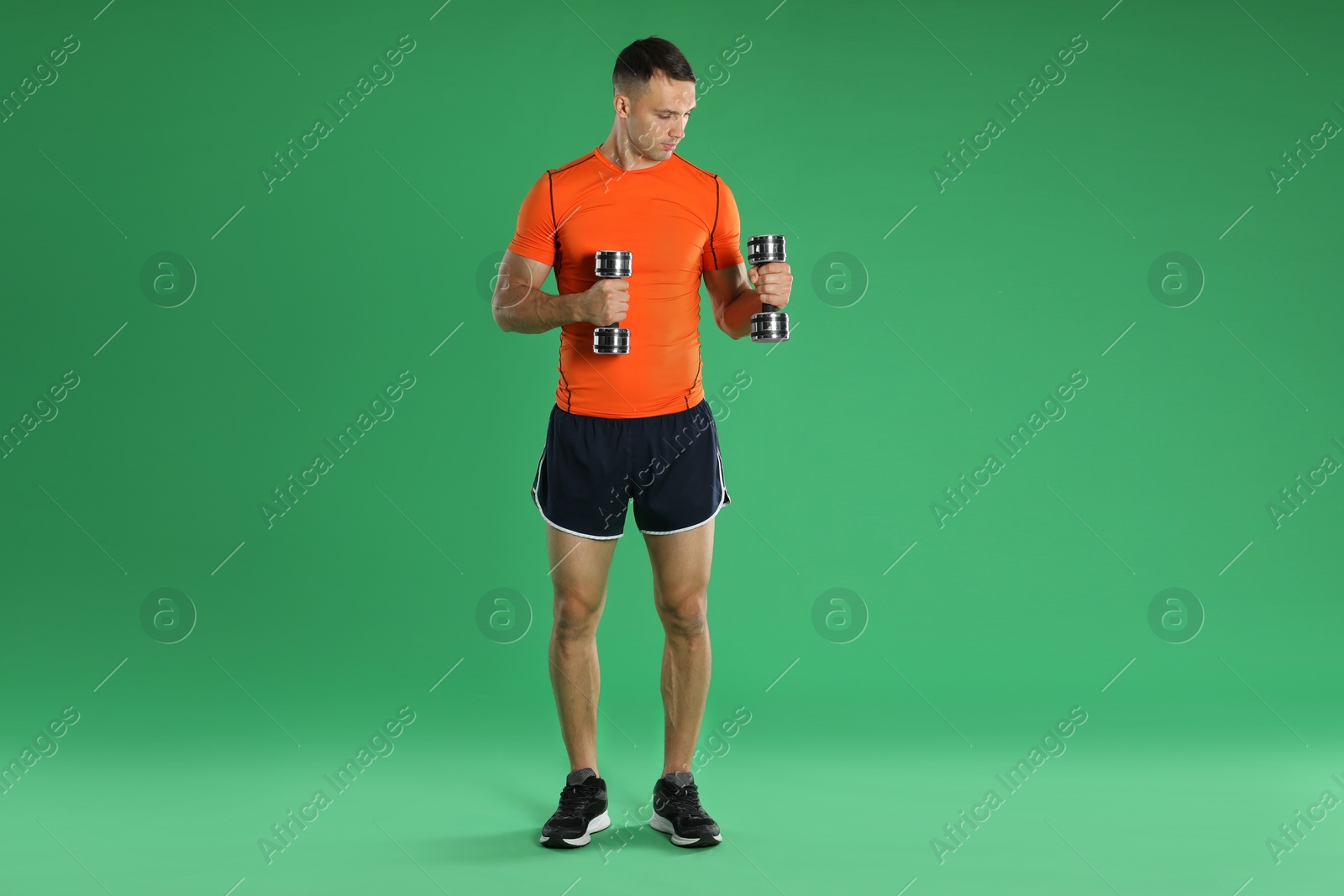 Photo of Man exercising with dumbbells on green background