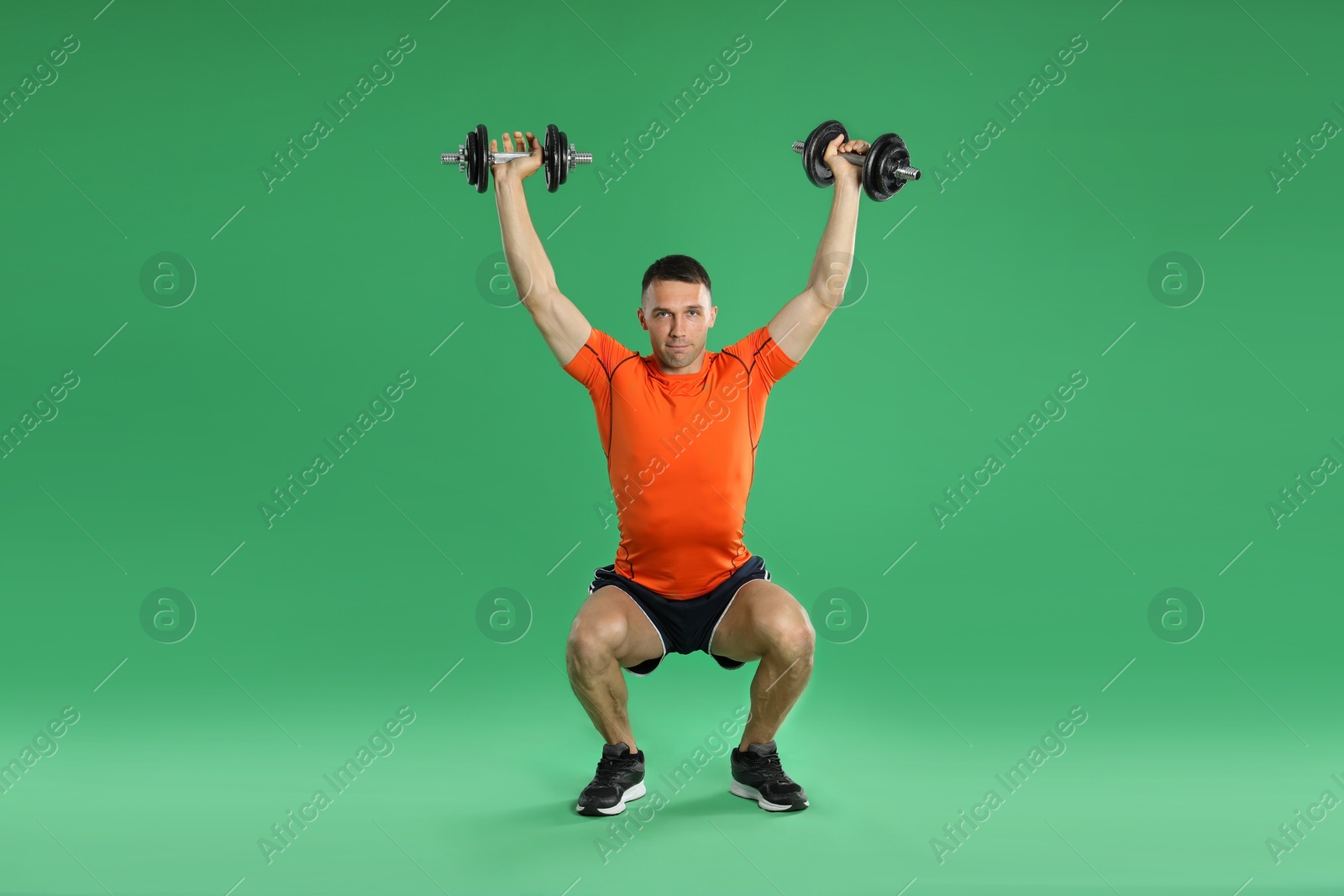 Photo of Man exercising with barbells on green background