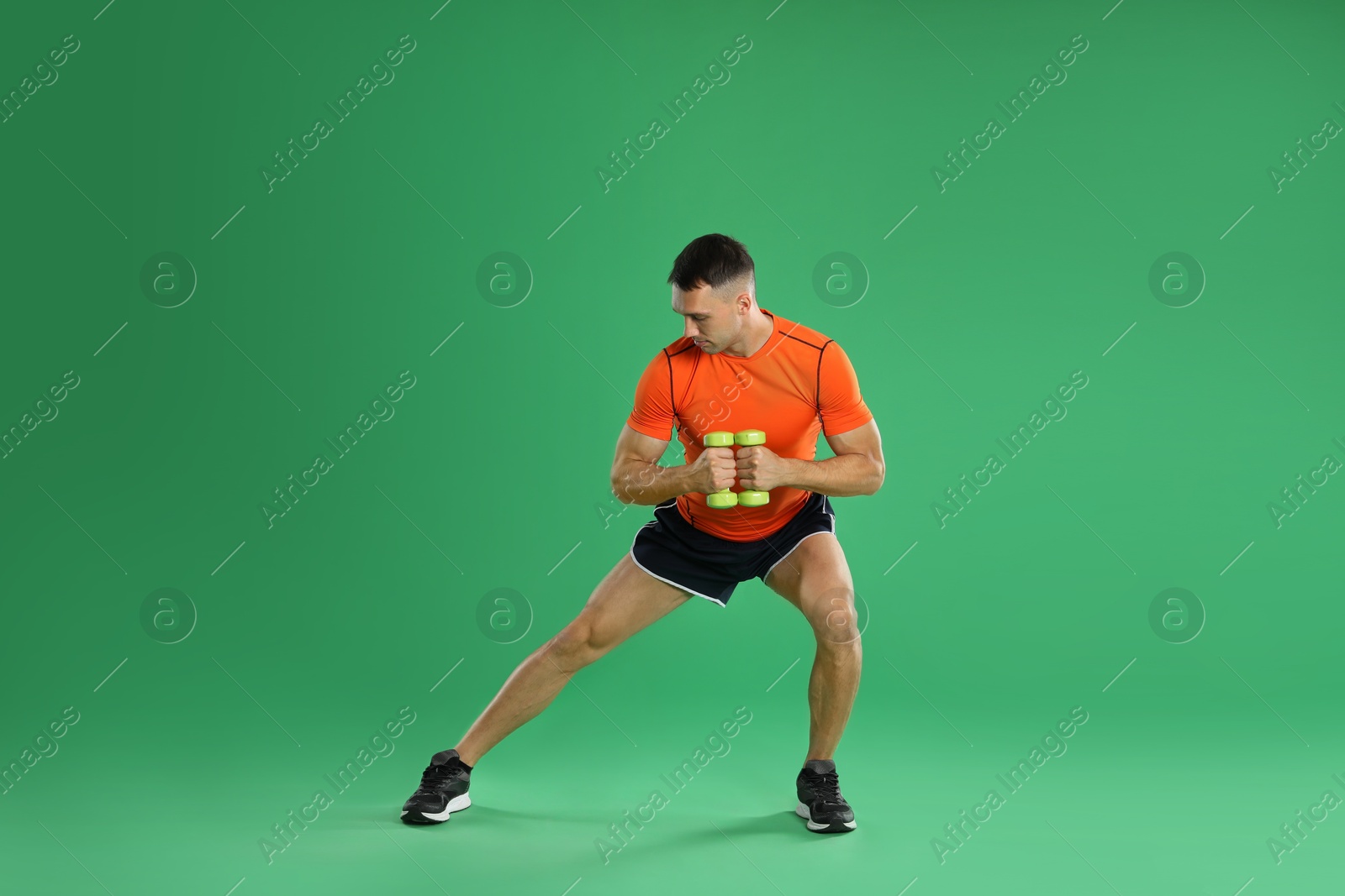 Photo of Man exercising with dumbbells on green background