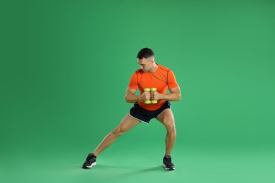 Photo of Man exercising with dumbbells on green background