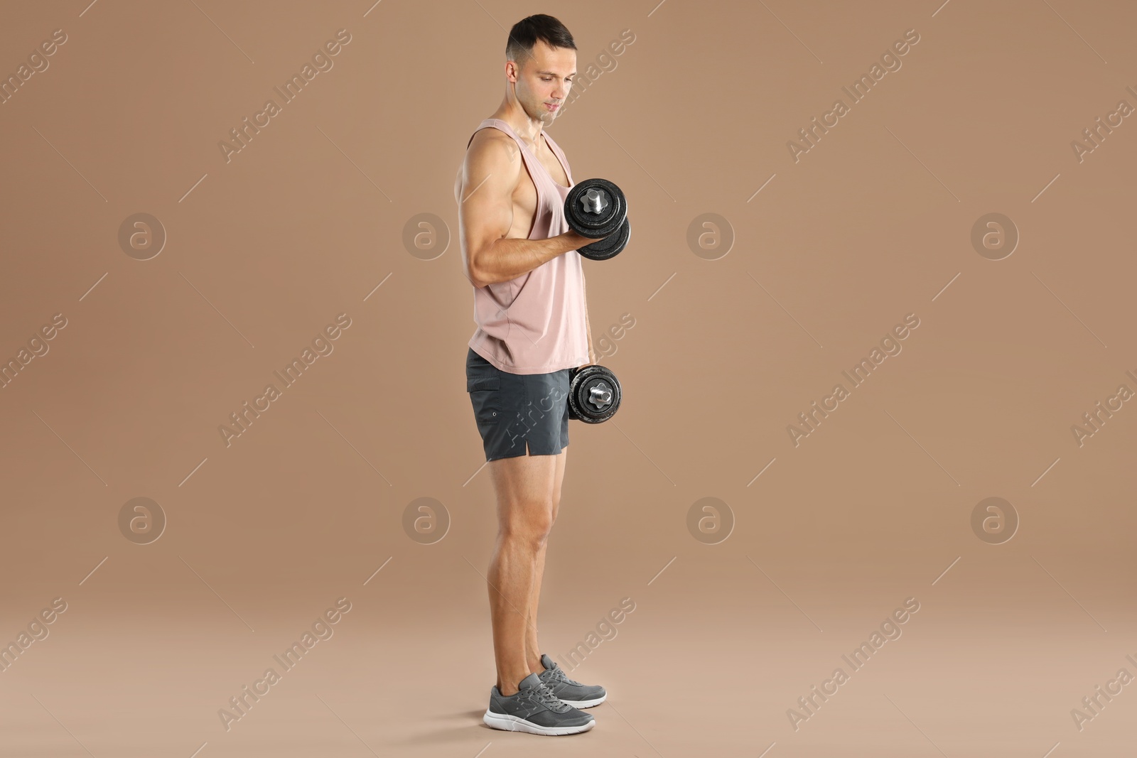 Photo of Man exercising with barbells on light brown background