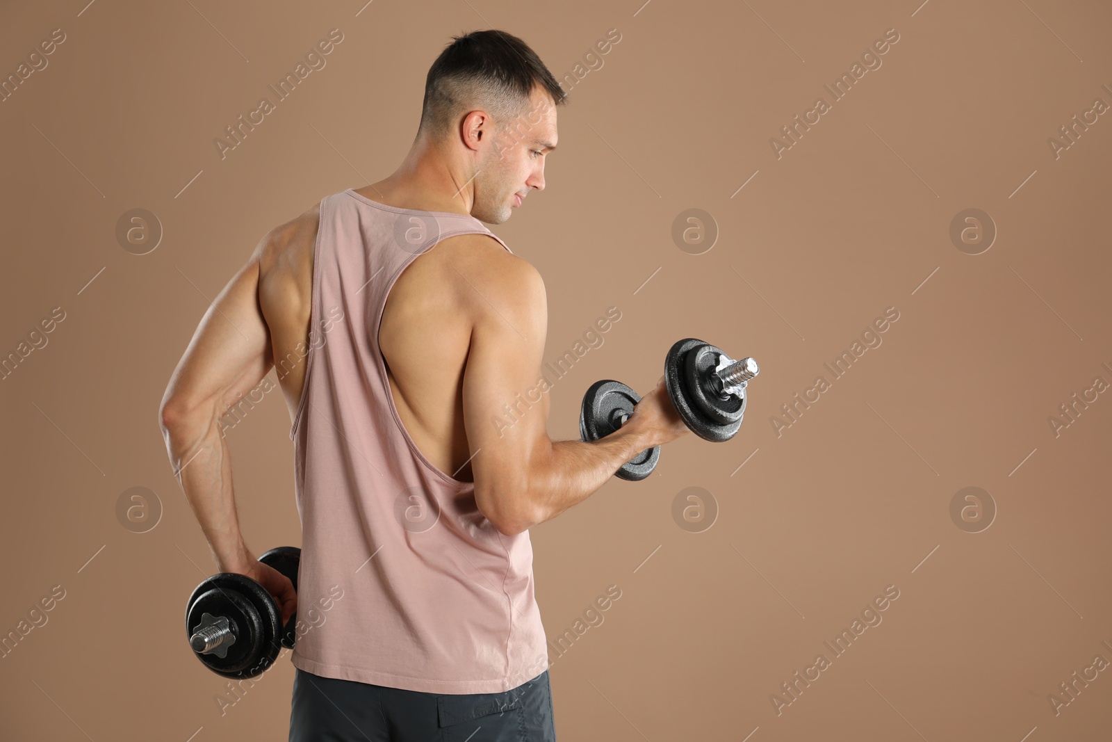 Photo of Man exercising with barbells on light brown background, space for text