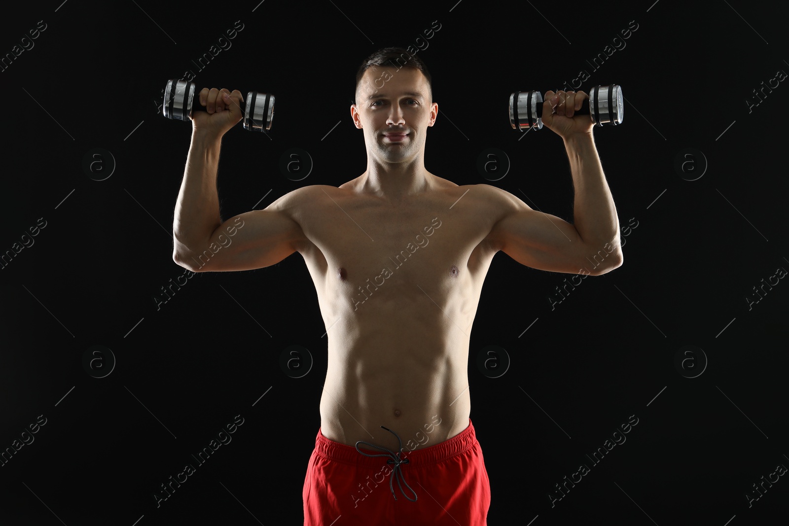 Photo of Man exercising with dumbbells on black background