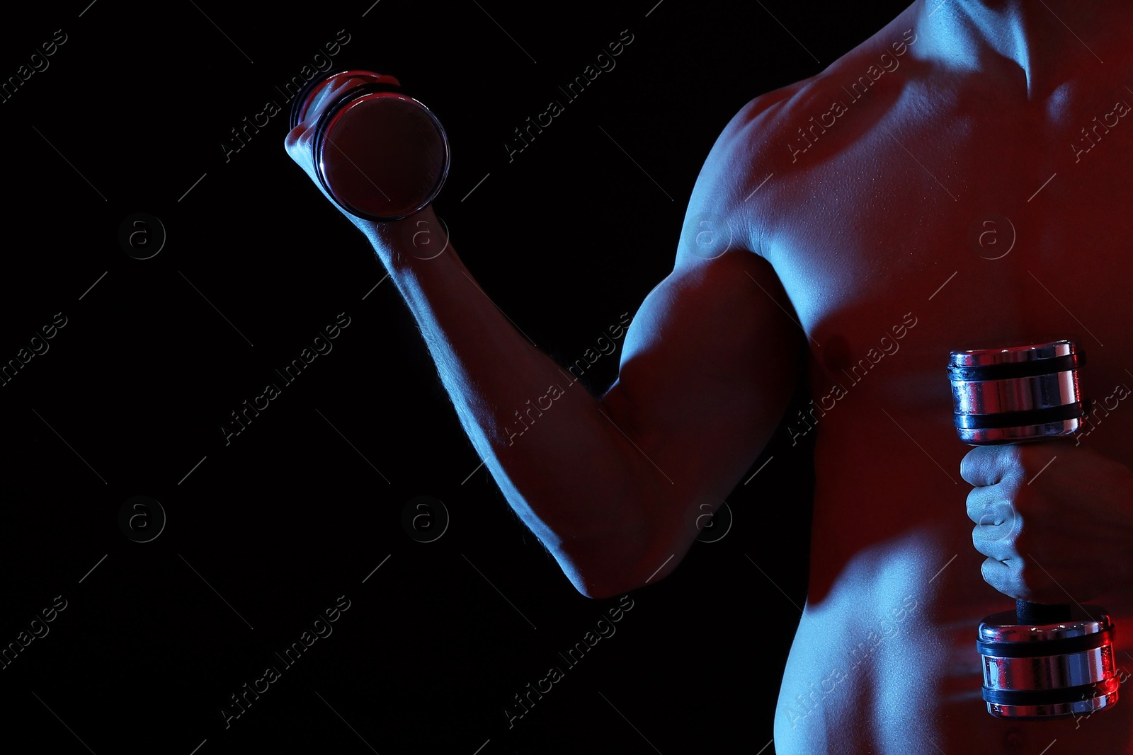 Photo of Man exercising with dumbbells on black background, closeup